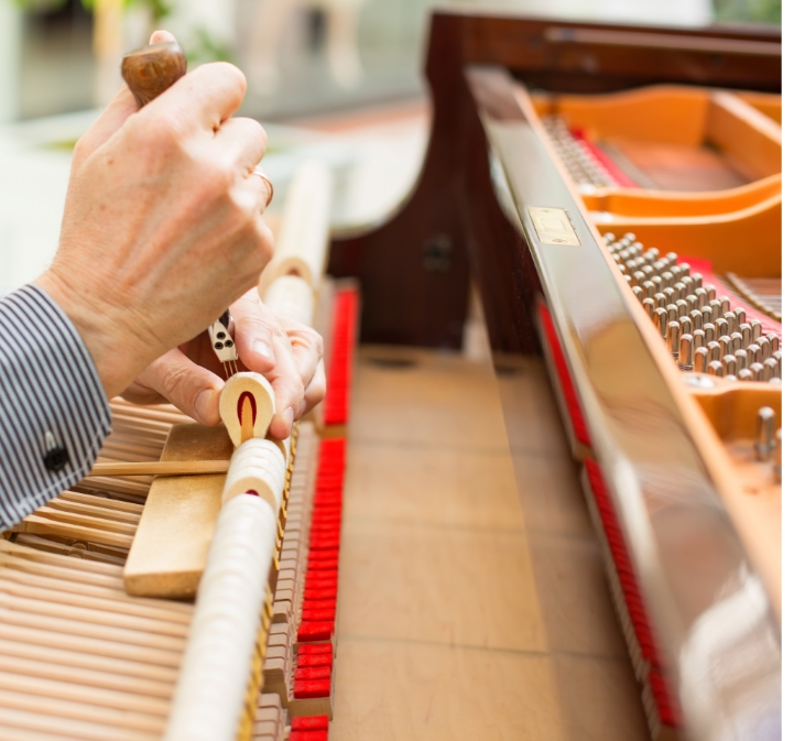 Piano Reparatie of revisie 2 Handen van een pianotechnicus aan het mechaniek van een piano