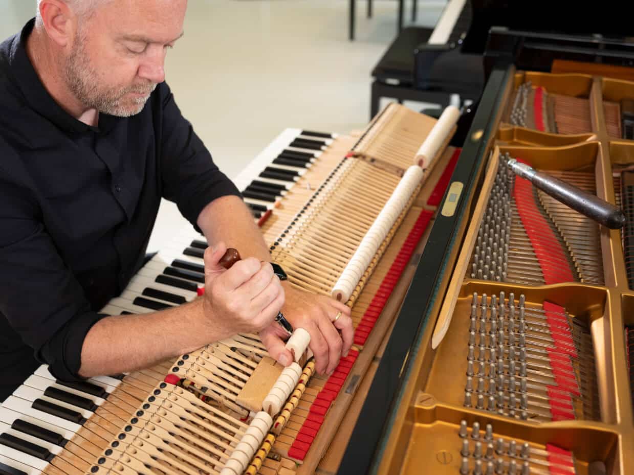 Medewerker van Schumer repareerd een piano